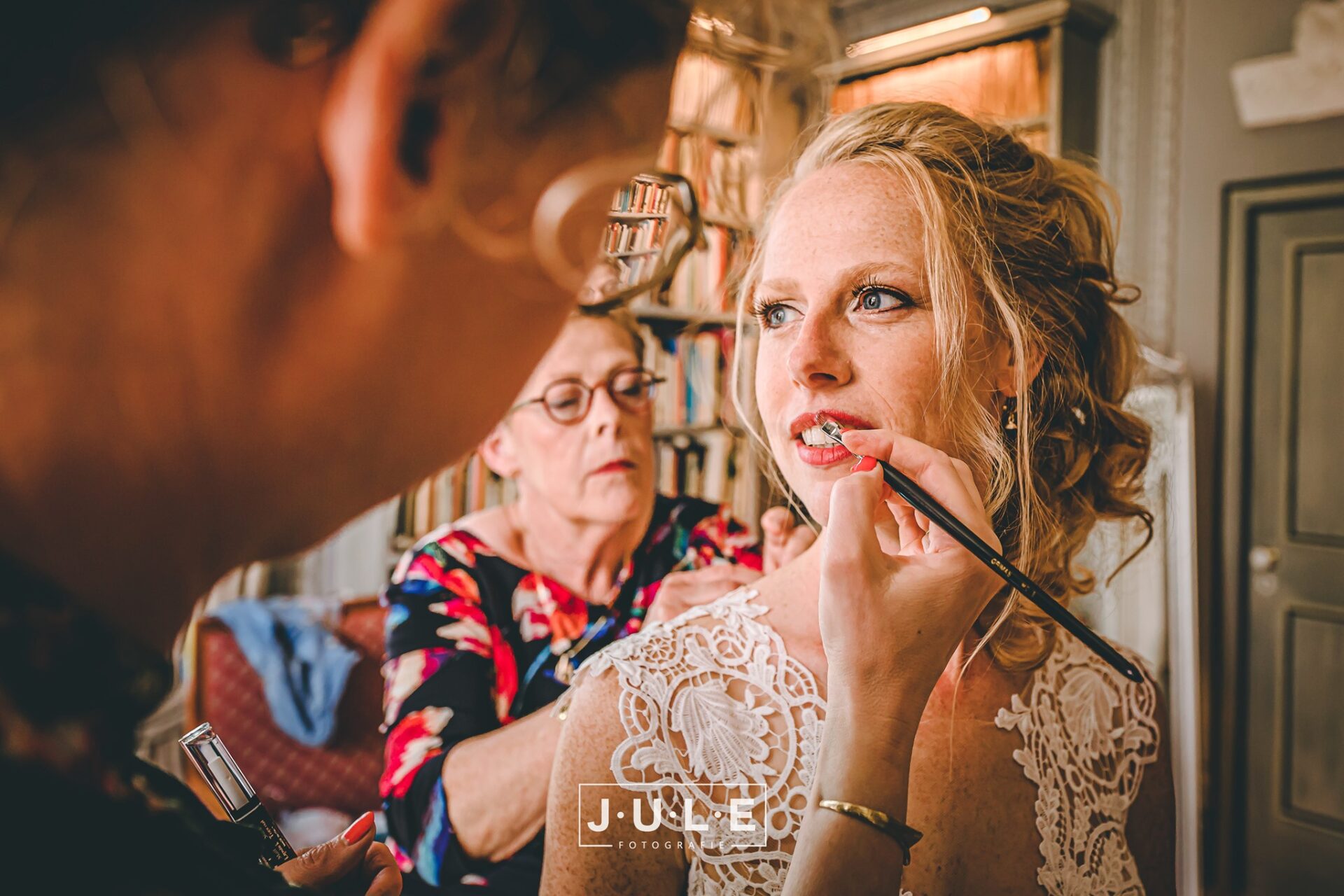 Anja werkt make-up van bruid bij terwijl ze haar bruidsjurk aantrekt