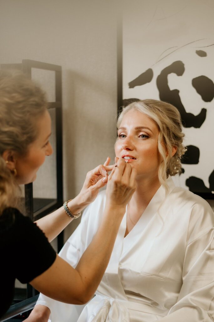 Bruidsmake-up waarbij lippenstift wordt aangebracht bij een bruid in kimono