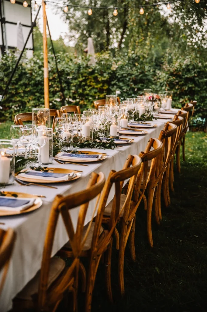Dineren aan lange tafels met houten crosschairs in een romantische tuin setting