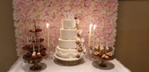 Bruidstaart in amerikaanse stijl met handgespoten decoratie voor een bloemenmuur