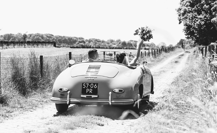 Klassieke speedster trouwauto met bruidspaar erin