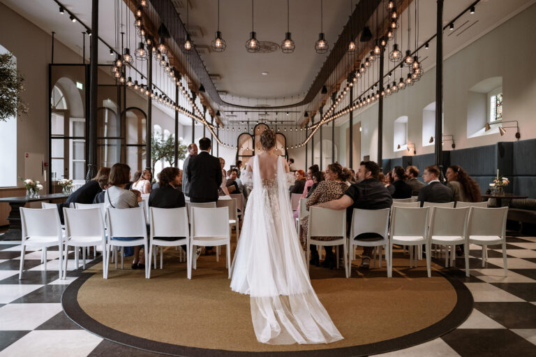 Bruid met sluier loopt door gangpad naar ceremonie