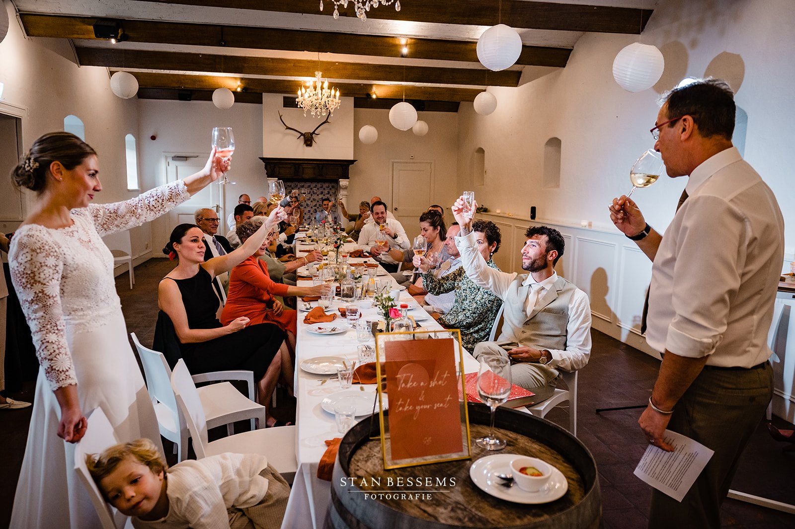 Bruidspaar met gasten proost aan tafel bij diner binnen Landgoed Kasteel Limbricht