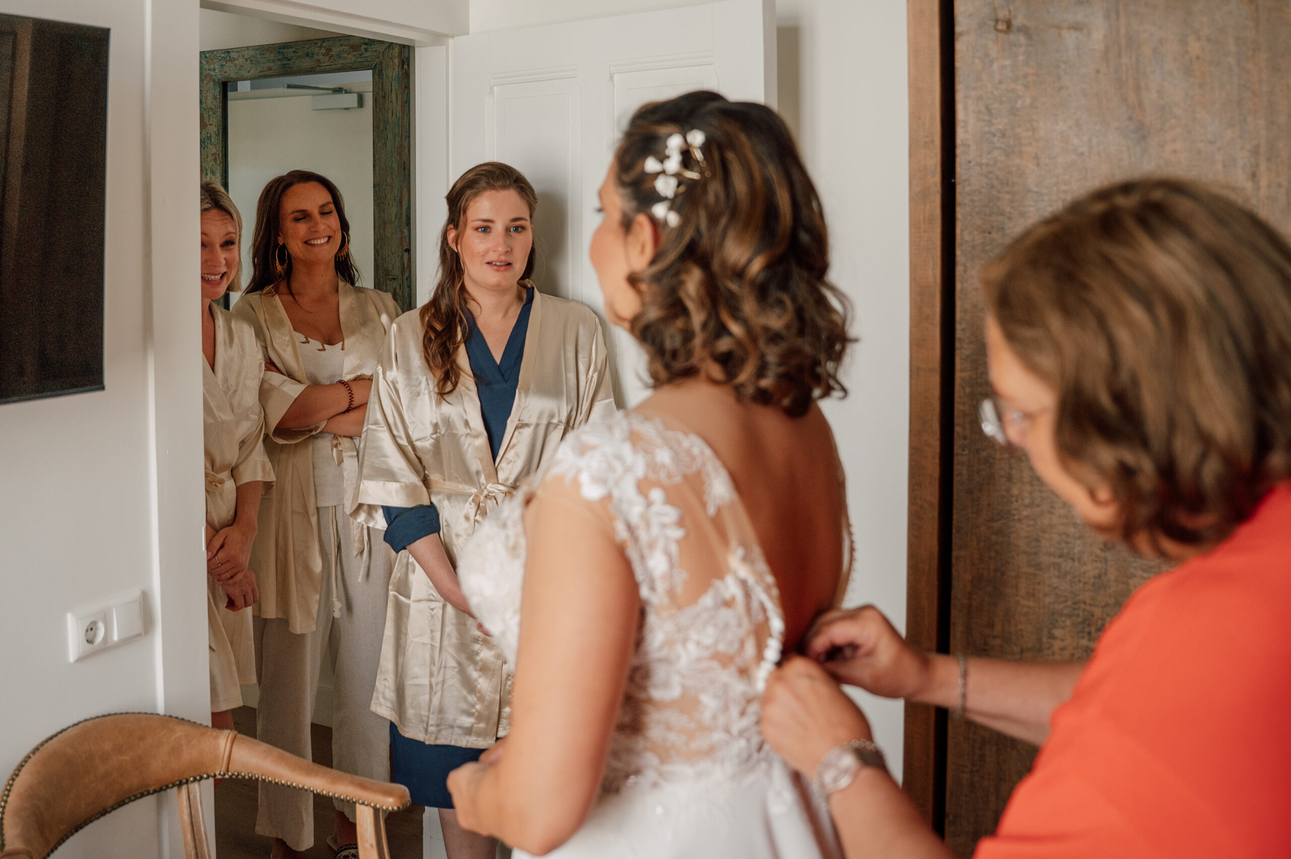 Bruidsmeisjes helpen met aantrekken van bruidsjurk