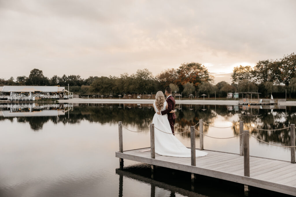 Bruidspaar op steiger aan het water bij Beachclub Degreez