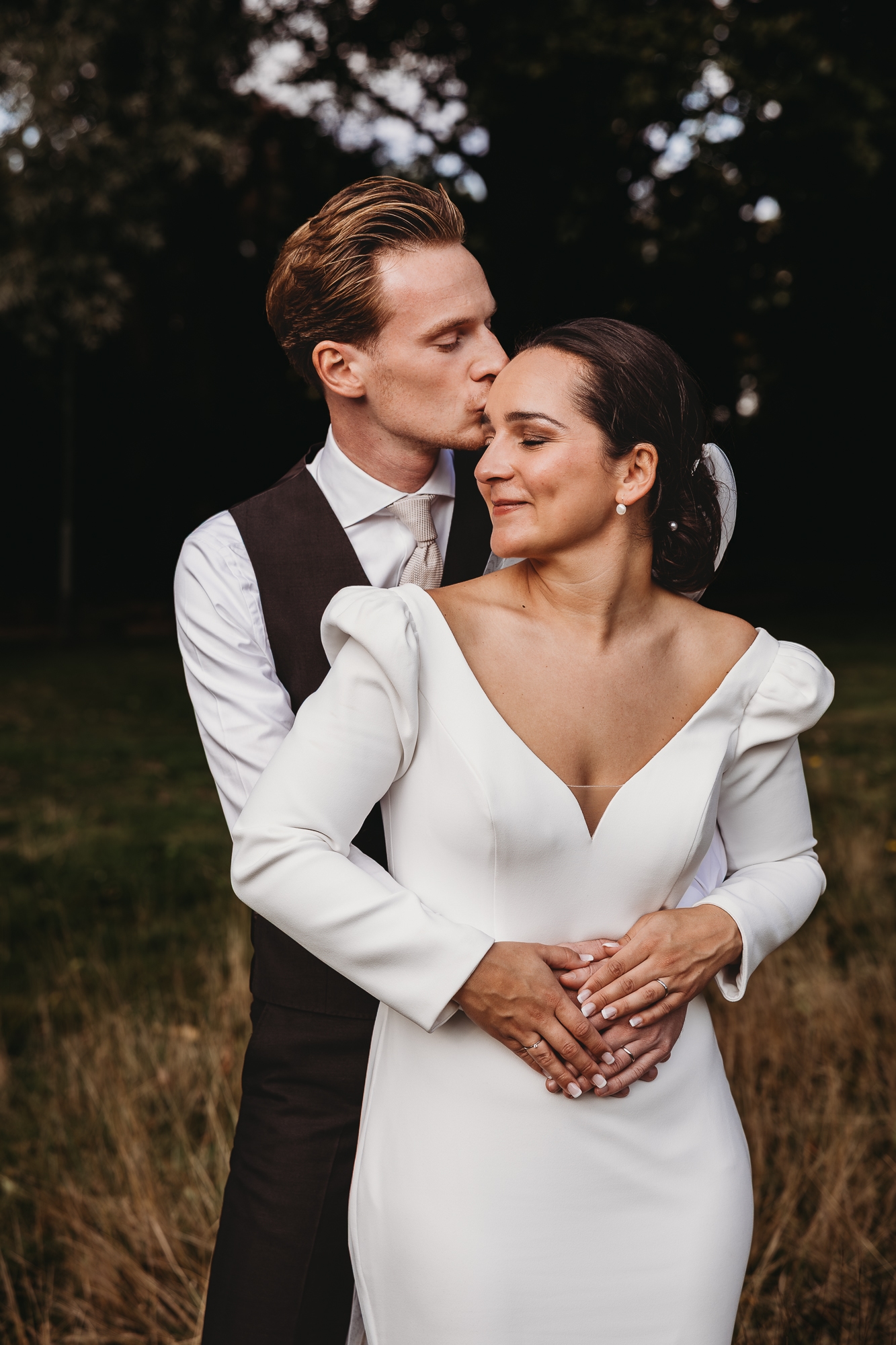 Bruidspaar in het warme herfstlicht met jurk met lange mouwen en zwart pak