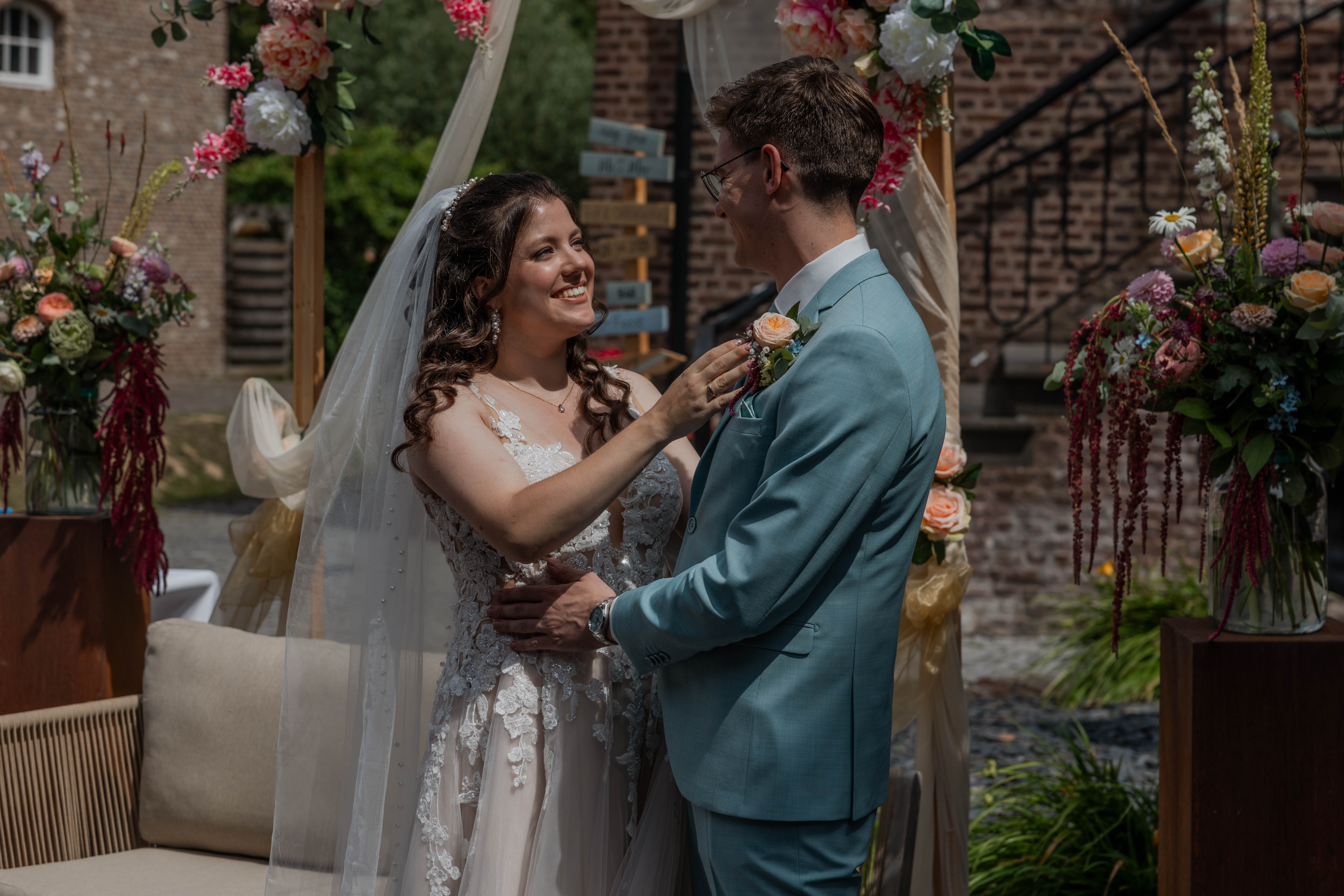 Bruidspaar kijkt elkaar lachend aan voor backdrop ceremonie