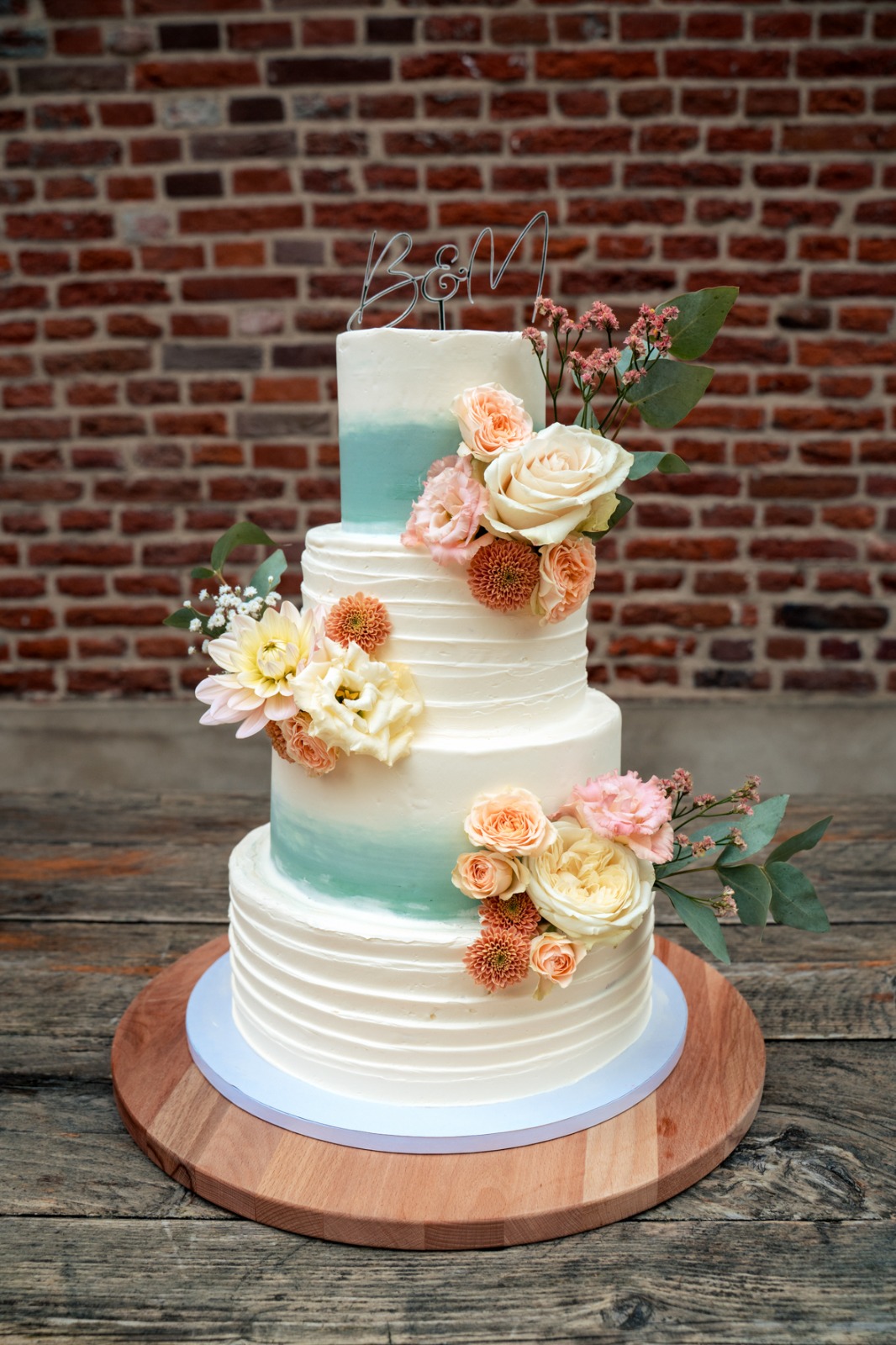 Traditionele vierlaags bruidstaart met lichtblauw accent en bloemen