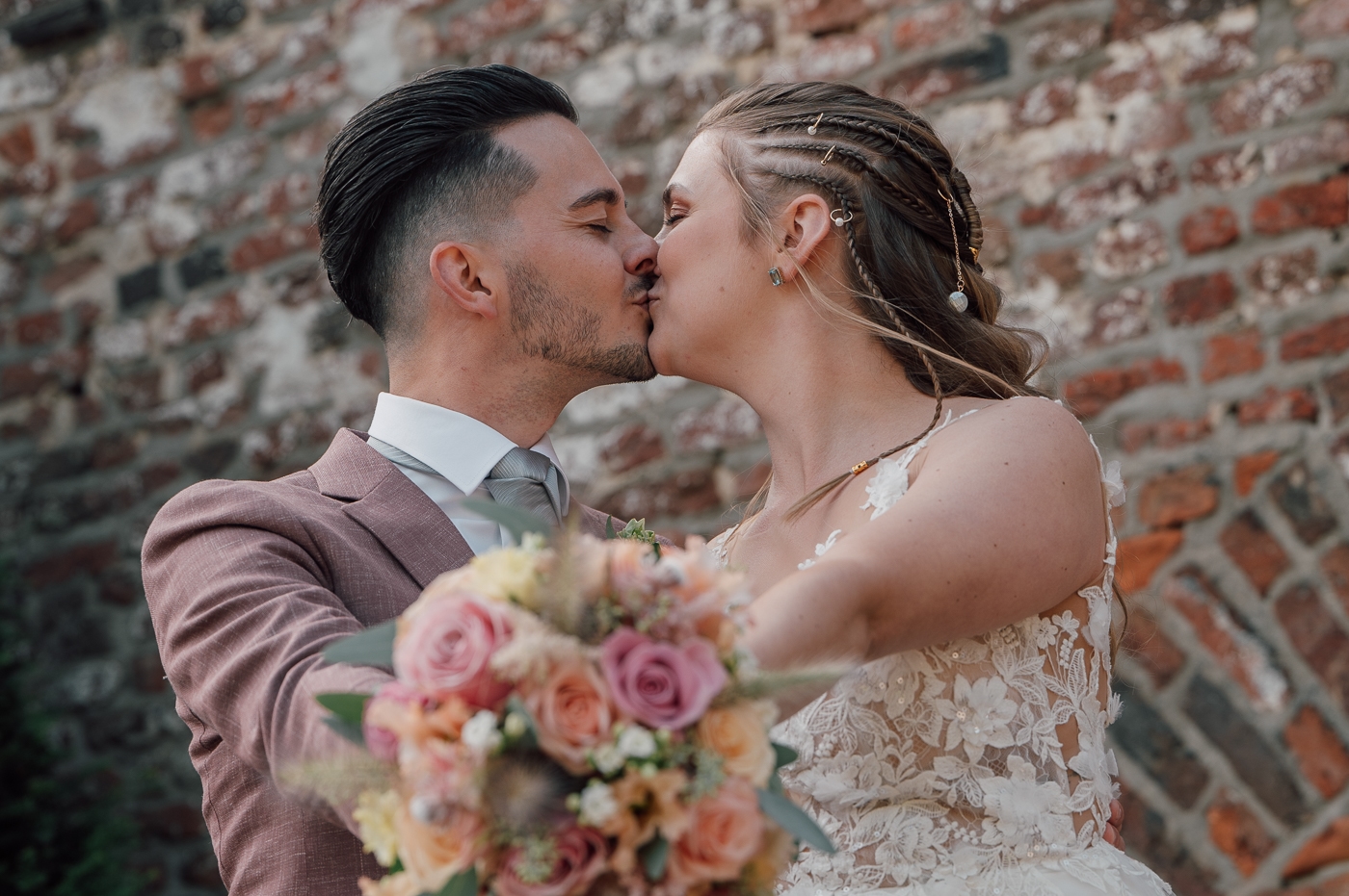 Bruidspaar kust elkaar met bruidsboeket uitstekend naar de camera