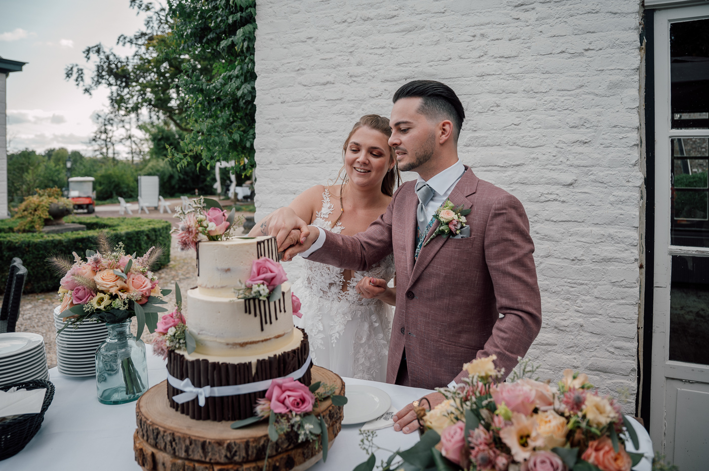 Bruidspaar snijdt bruidstaart aan met verschillende lagen en bloemen