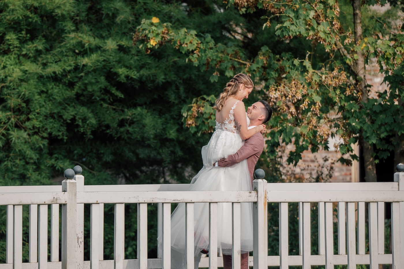 Bruidegom tilt bruid op op bruggetje bij kasteel
