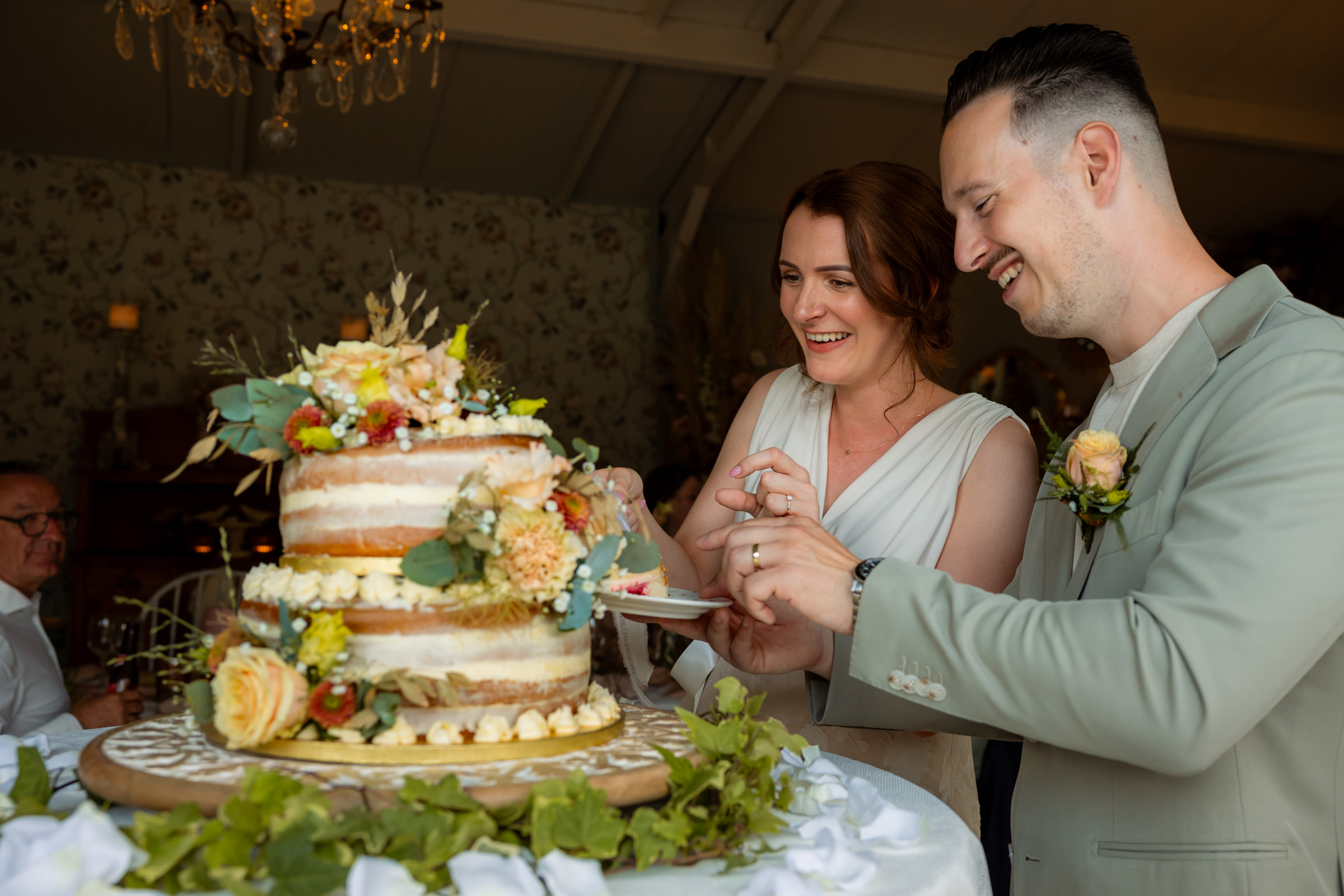 Aansnijden van tweelaagse taart door bruidspaar