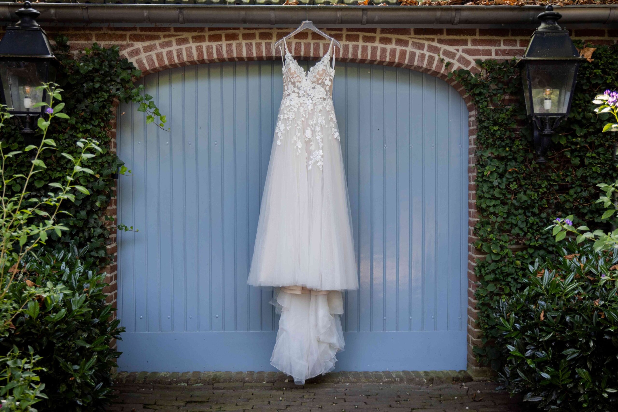 Bruidsjurk hangt klaar voor lichtblauwe poort