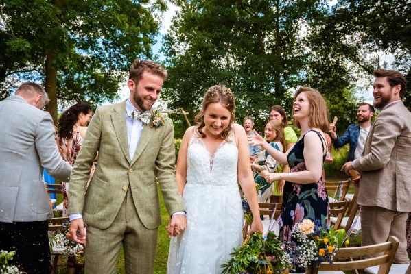 Bruidspaar loopt hand in hand weg bij de ceremonie