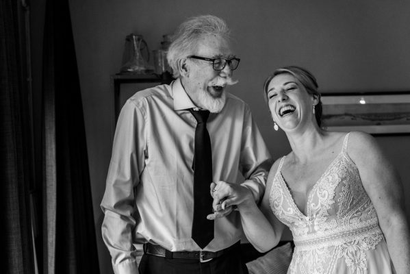 Bruid lachend met vader in zwart-wit