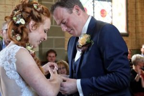 Bruidspaar schuift ringen om vingers tijdens huwelijksceremonie in Clemensdomein