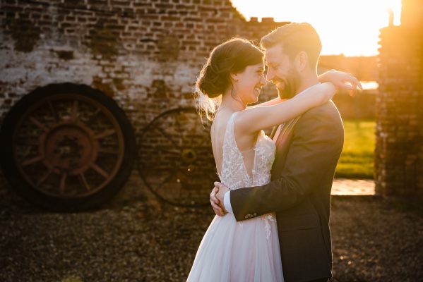 Bruidspaar met zonsondergang bij mooie oude muur