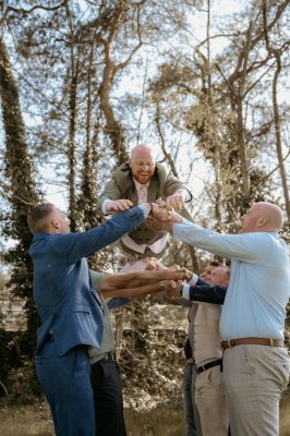 Spontane foto waar bruidegom door gasten in de lucht wordt gegooid