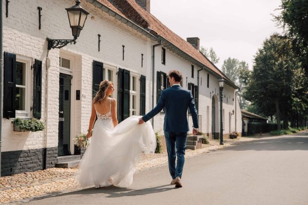 Bruidspaar waarvan de bruidegom de bruidsjurk omhoog houdt lopend in Thorn