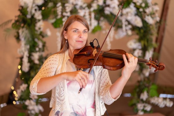 Portret van violiste Joyce voor bloemenwand