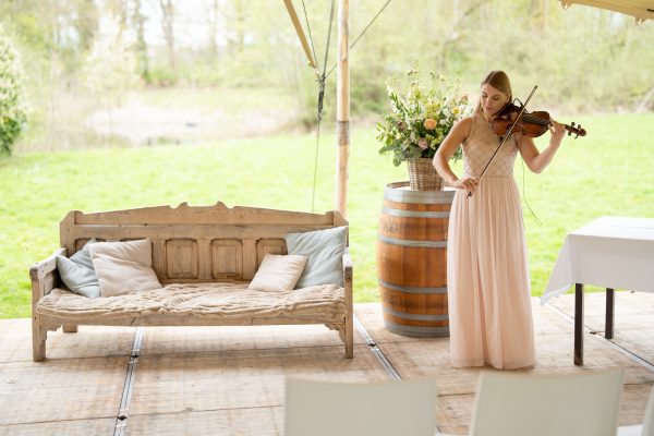 Violiste staat naast bankje bruidspaar