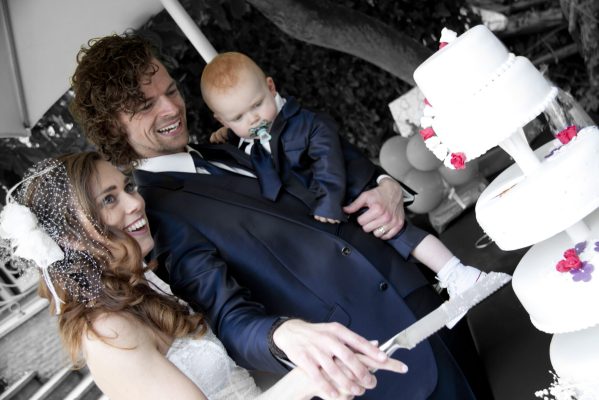 Aansnijden van bruidstaart met kindje op de arm