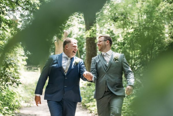 Lachende bruidegommen hand in hand in de natuur