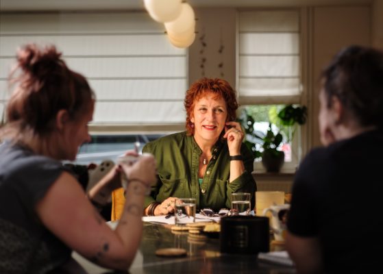 Trouwambtenaar met bruidspaar lachend tussen schouders door