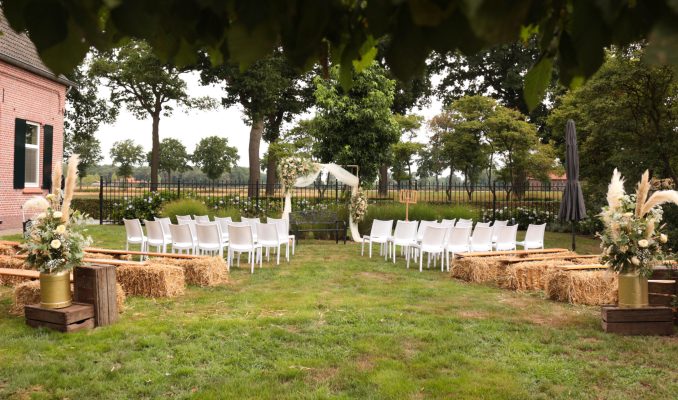 Ceremonie opstelling met witte stoelen en strobalen