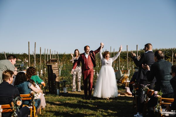 Bruidspaar juichend na ceremonie tussen de wijnranken in Zuid-Limburg bij Wijngoed Fromberg