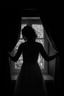Bruid tussen gordijnen in zwart wit