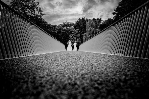 Bruidspaar in zwart wit over brug