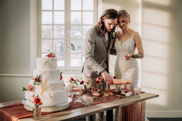 Bruidspaar snijdt taart aan in trouwpak en bruidsjurk