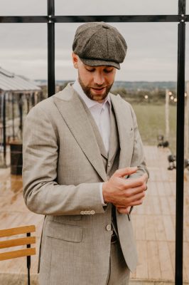 Bruidegom in lichtgekleurd maatpak met pet