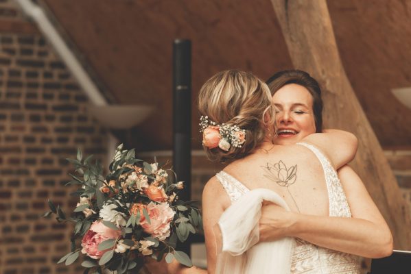 Zangeres geeft bruid een knuffel met bruidsboeket vast